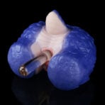 Close-up of a blue dental impression material surrounding a pink gum model with a metal dental instrument inserted into the area.