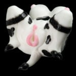 Cow-patterned silicone sex toy with pink udder area and black strap bindings on a black background.
