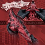 Close-up of a red silicone dragon pussy sex toy labeled 'Liquid Platinum Silicone' being held by gloved hands in a bold ad.