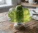 Half a cucumber is stuck in the jelly in a bowl, which is being heated from below; the caption reads, “What Is Cockwarming?”